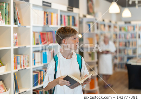 Teenage boy choosing books in large bookstore Teenage boy choosing books in large bookstore 142777381