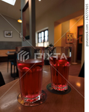 Two raspberry drinks resting on coasters in a cozy restaurant setting Two raspberry drinks resting on coasters in a cozy restaurant setting 142777605