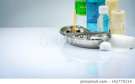 Wound care supplies with stainless steel kidney dish, surgical forceps, sterile gauze, cotton ball, elastic bandages and antiseptic solution on a white background. Medical wound dressing equipment. Wound care supplies with stainless steel kidney dish, surgical forceps, sterile gauze, cotton ball, elastic bandages and antiseptic solution on a white background. Medical wound dressing equipment. 142779154