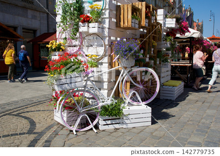 Wroclaw, Poland, June 16, 2018: Decorative white bicycle with colorful flowers at Market Square Wroclaw, Poland, June 16, 2018: Decorative white bicycle with colorful flowers at Market Square 142779735