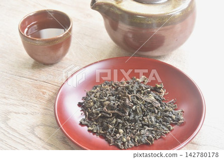 dry Chinese tea leaves with pottery pot and glass on table 142780178