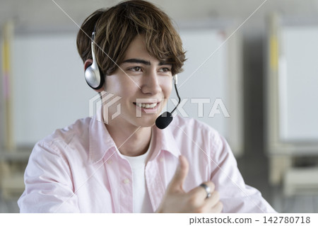 一位戴著耳機說話的年輕外國男子。 一位戴著耳機說話的年輕外國男子。 142780718