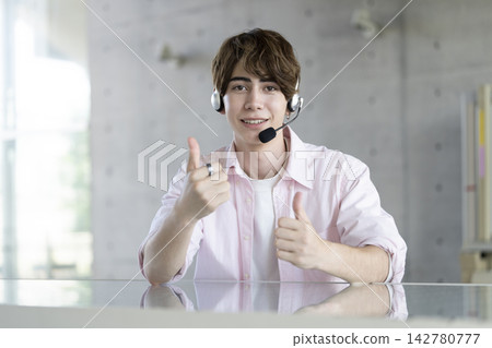 A young foreign man smiles and gives a thumbs-up while looking at the camera. A young foreign man smiles and gives a thumbs-up while looking at the camera. 142780777