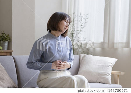 一位年近五十的女子摀著肚子。 142780971