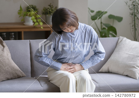 50出頭的女人摀著小腹 50出頭的女人摀著小腹 142780972