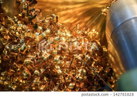 Piles of continuous brass material chips from a turning process on a lathe machine Piles of continuous brass material chips from a turning process on a lathe machine 142781028