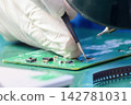 Skilled operator soldering an electronic circuit board while wearing protective rubber gloves 142781031