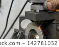 Skilled operator manually regrinding a flat nose end mill on a tool regrinding machine 142781032