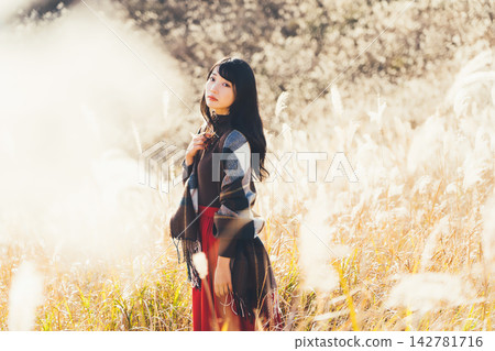 一位身披披肩、周圍環繞著蒲葦草的女子。 142781716