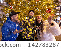 A happy family of three joyfully celebrates the New Year outside 142783287