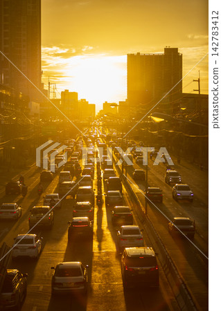 Golden hour traffic jam on a busy highway with tall buildings at sunset Golden hour traffic jam on a busy highway with tall buildings at sunset 142783412