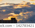 Dramatic sunset clouds illuminate apartment building rooftop with antennas 142783421