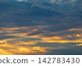 Dramatic sunset sky with golden and dark blue clouds creating a beautiful natural spectacle 142783430