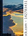 Dramatic sunset clouds illuminated by golden light over city buildings 142783431