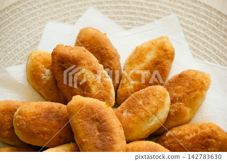 Freshly baked golden pirozhki pies placed on plate for bakery banner Freshly baked golden pirozhki pies placed on plate for bakery banner 142783630