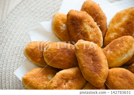 Freshly baked golden pirozhki pies placed on plate for bakery banner Freshly baked golden pirozhki pies placed on plate for bakery banner 142783631