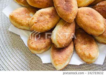 Freshly baked golden pirozhki pies placed on plate for bakery banner Freshly baked golden pirozhki pies placed on plate for bakery banner 142783632