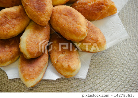 Freshly baked golden pirozhki pies placed on plate for bakery banner Freshly baked golden pirozhki pies placed on plate for bakery banner 142783633
