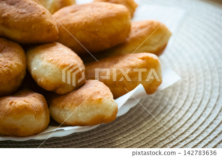 Golden fried pirozhki pies stacked on plate for bakery menu Golden fried pirozhki pies stacked on plate for bakery menu 142783636