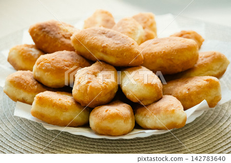 Stack of golden fried pirozhki pies served on plate for bakery design Stack of golden fried pirozhki pies served on plate for bakery design 142783640