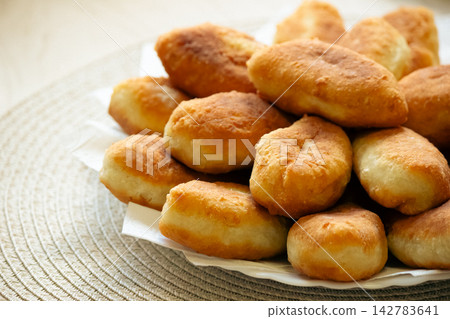 Stack of golden fried pirozhki pies served on plate for bakery design Stack of golden fried pirozhki pies served on plate for bakery design 142783641