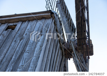 Old wooden windmill rotates showing weathered wood grain and metal fasteners Old wooden windmill rotates showing weathered wood grain and metal fasteners 142784037