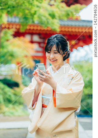 A woman in a kimono praying at a shrine 142784616