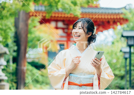 A woman in a kimono praying at a shrine 142784617