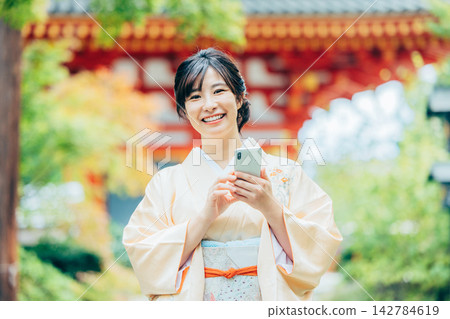 A woman in a kimono praying at a shrine 142784619