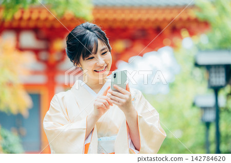 A woman in a kimono praying at a shrine 142784620