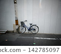 城市裡，一輛藍色自行車停在電線桿旁，建築工地上豎立了臨時圍籬。 142785097