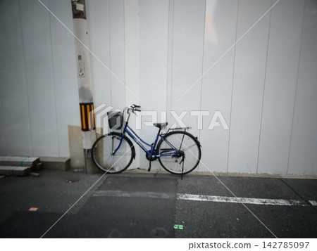 城市裡,一輛藍色自行車停在電線桿旁,建築工地上豎立了臨時圍籬。 城市裡,一輛藍色自行車停在電線桿旁,建築工地上豎立了臨時圍籬。 142785097