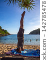 A man doing yoga in headstand pose on Yanui Beach. 142785478