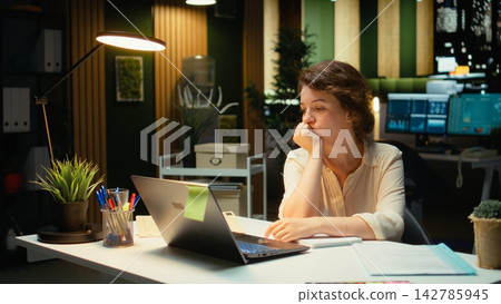 Businesswoman makes mistake in transcribing finance updates on notebook, tearing up the paper sheet and restarting. Discontent impatient worker wanting to finish tasks for the night. Camera A. 142785945