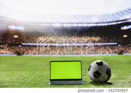 Green screen on laptop mockup with soccer ball arranged on wide stadium pitch with blurred stands, leaving editable space for sports advertising. Screen replacement. Green screen on laptop mockup with soccer ball arranged on wide stadium pitch with blurred stands, leaving editable space for sports advertising. Screen replacement. 142785957