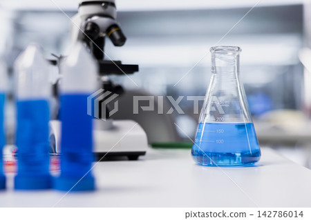 Close up of blue liquid chemical samples in empty clinical lab used by biologists to analyze properties. Compound vials glassware in research facility used for RD studies with no people in Close up of blue liquid chemical samples in empty clinical lab used by biologists to analyze properties. Compound vials glassware in research facility used for RD studies with no people in 142786014