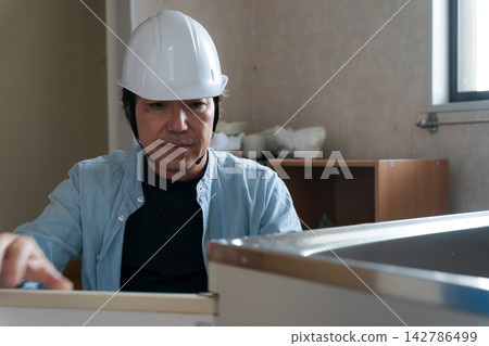 A male worker remodeling a kitchen. A male worker remodeling a kitchen. 142786499
