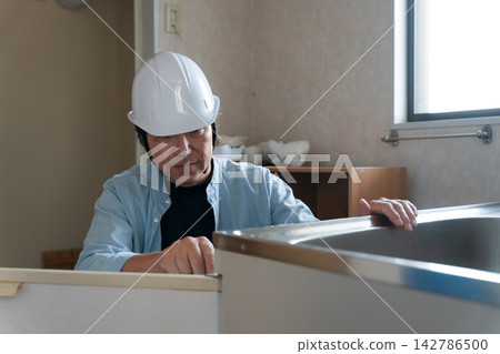 A male worker remodeling a kitchen. A male worker remodeling a kitchen. 142786500