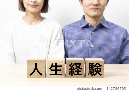 一塊標示「人生經驗」的方塊和一對中年夫婦。 一塊標示「人生經驗」的方塊和一對中年夫婦。 142786705