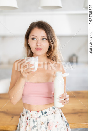 Young woman in skirt drinking kefir in kitchen Young woman in skirt drinking kefir in kitchen 142786895