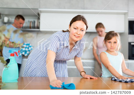 Little girl helps mother wash kitchen table. Little girl helps mother wash kitchen table. 142787009