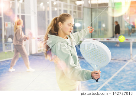 Padel game - teen girl actively kicks ball during a padel game 142787013