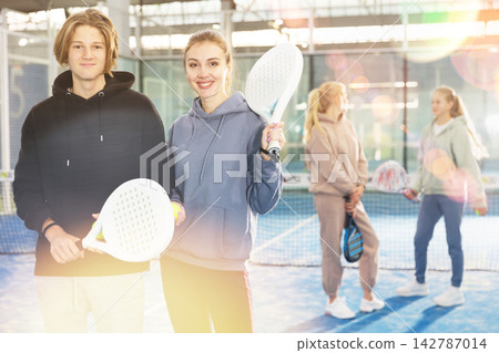 Portrait of guy and girl on an open court playing padel Portrait of guy and girl on an open court playing padel 142787014