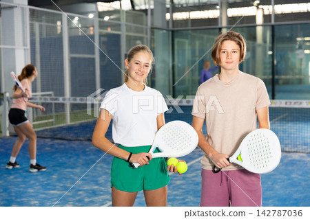Portrait of two teenage tennis players standing holding padel rackets and balls 142787036