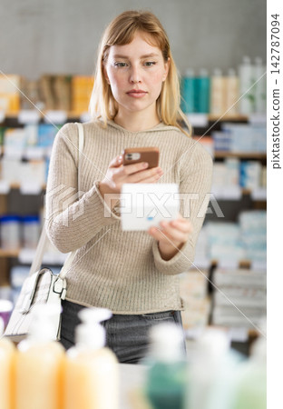 Girl in autumn clothes scans code on package of ointment to check expiration date Girl in autumn clothes scans code on package of ointment to check expiration date 142787094