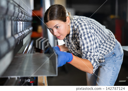 Metallurgical plant - female worker bending sheet of metal on press Metallurgical plant - female worker bending sheet of metal on press 142787124