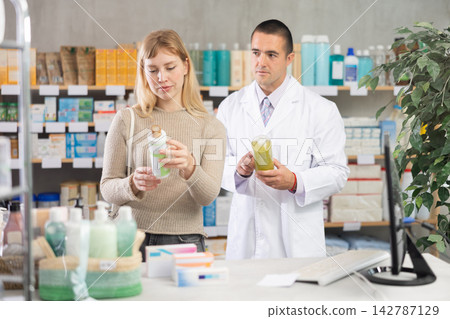In sales area, girl examines antidandruff shampoo, man pharmacist in background In sales area, girl examines antidandruff shampoo, man pharmacist in background 142787129