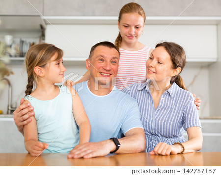 Portrait of happy family - father and mother with two children at table at home Portrait of happy family - father and mother with two children at table at home 142787137