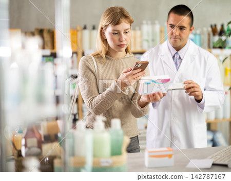 Young woman scanning QR-code on pills box while pharmacist offering 142787167