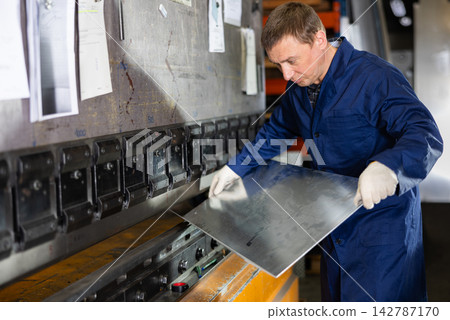 Adult man bends metal sheet under pressure Adult man bends metal sheet under pressure 142787170